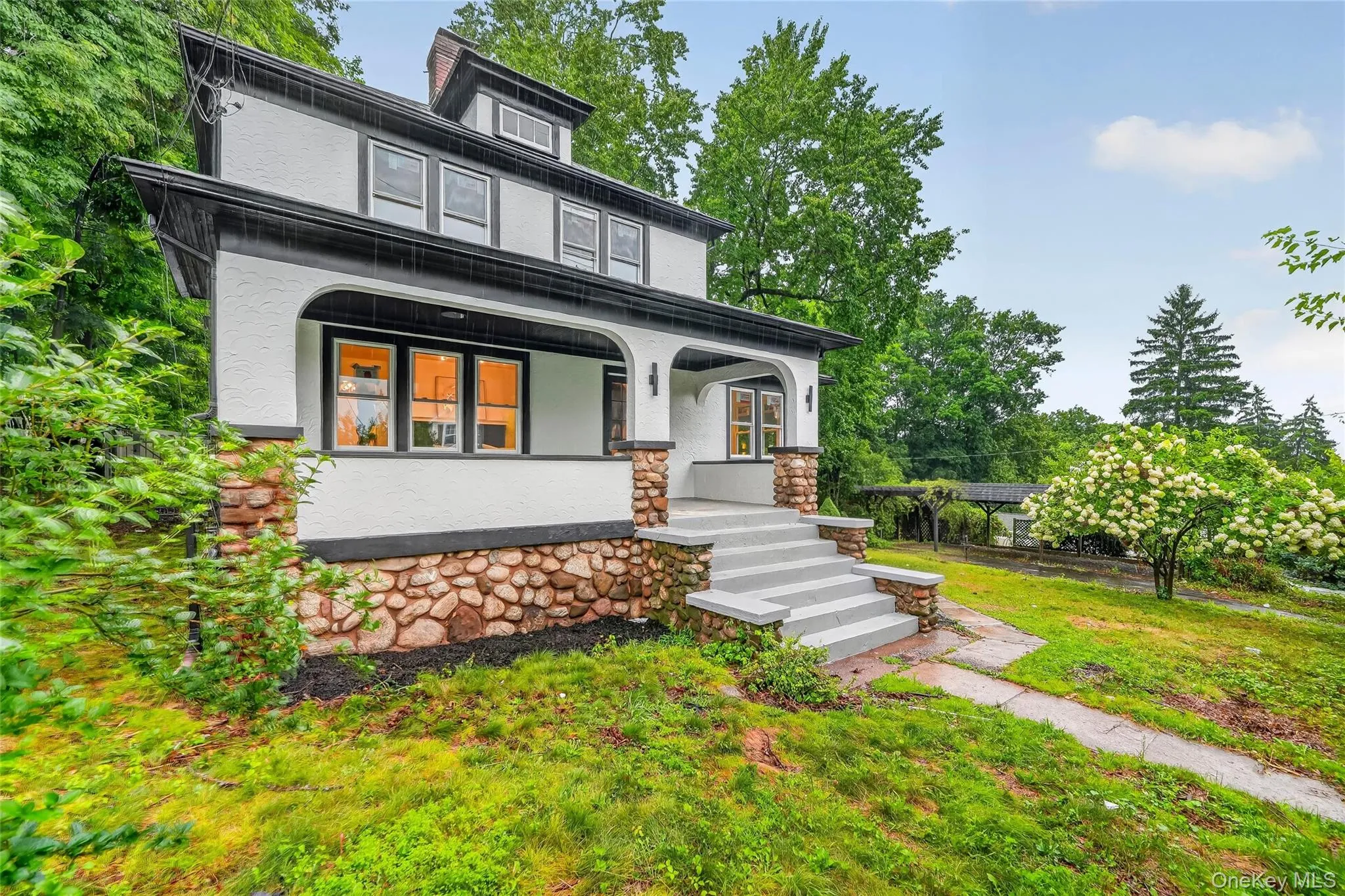 Stucco exterior featuring stone foundation detailing and a covered front porch Stucco exterior featuring stone foundation detailing and a covered front porch