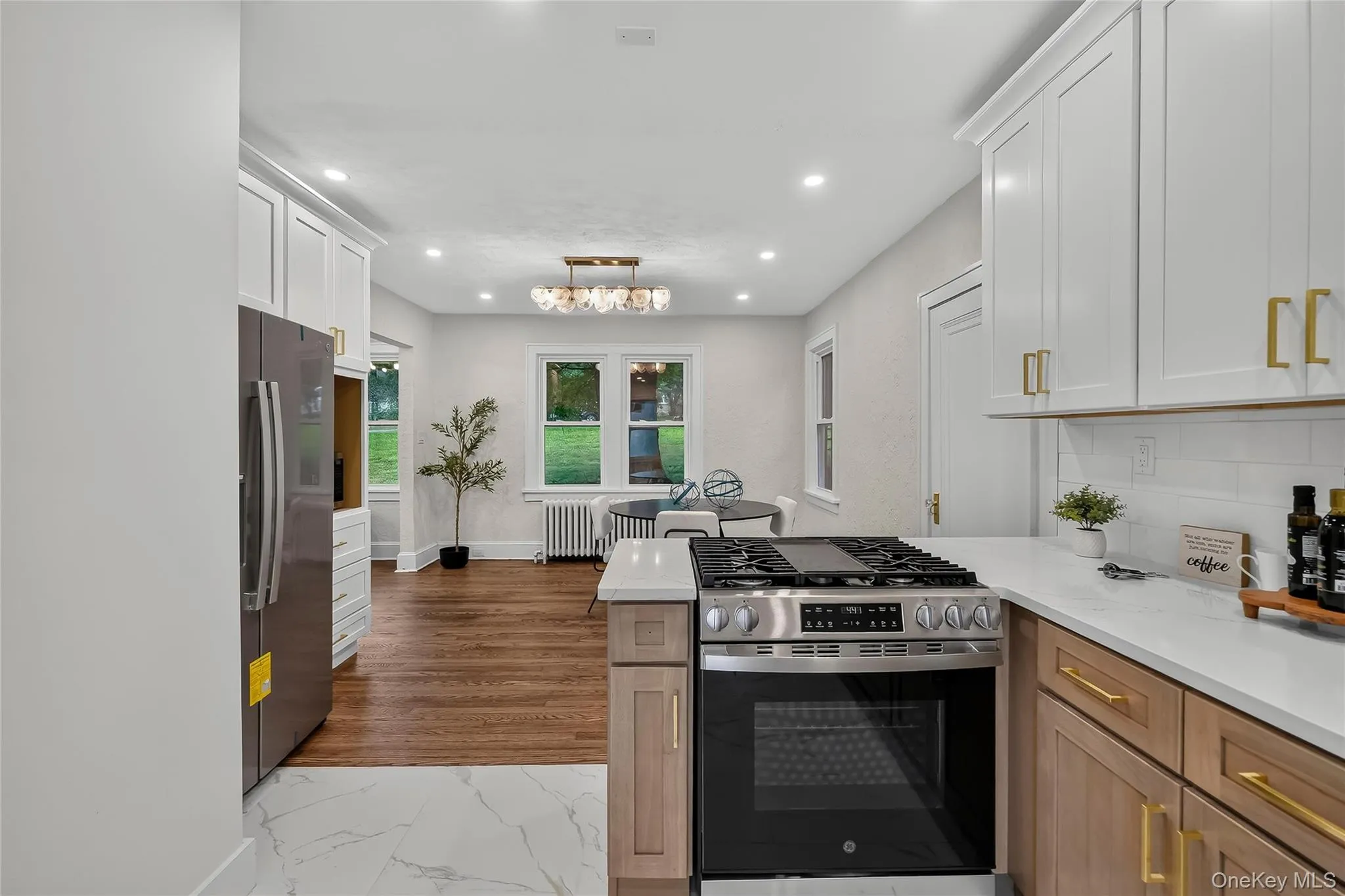Modern kitchen featuring white shaker upper cabinetry and natural wood lower cabinetry with gold-tone hardware Modern kitchen featuring white shaker upper cabinetry and natural wood lower cabinetry with gold-tone hardware