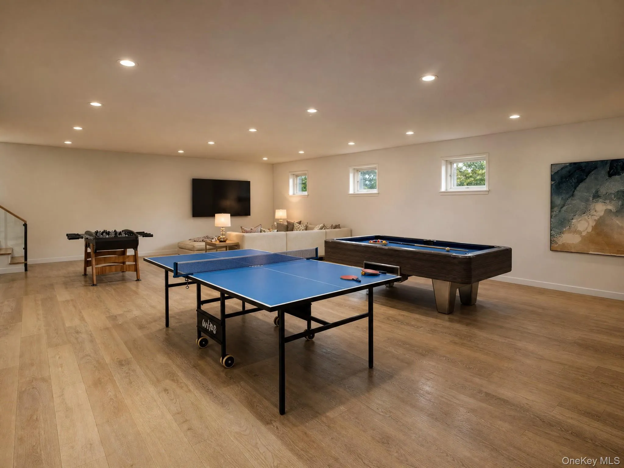 Spacious recreation room featuring wood-finish flooring, recessed lighting, and multiple windows Spacious recreation room featuring wood-finish flooring, recessed lighting, and multiple windows