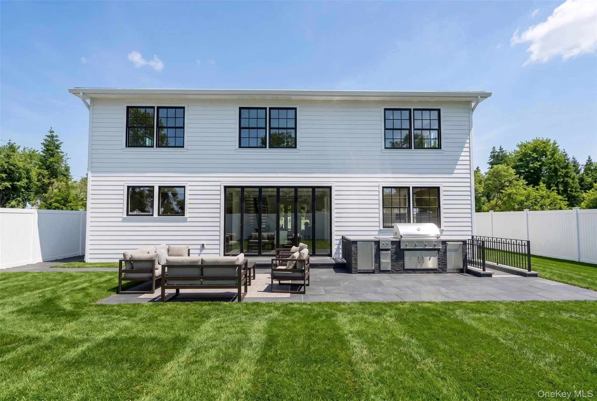 Expansive backyard featuring a manicured lawn and a spacious paver patio Expansive backyard featuring a manicured lawn and a spacious paver patio