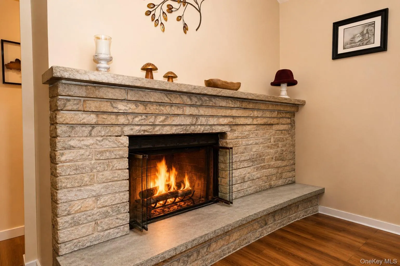 Stone-stacked fireplace with a substantial hearth and mantel, featuring a metal fire screen and wood-finish flooring - FP is showing digital enhancement Stone-stacked fireplace with a substantial hearth and mantel, featuring a metal fire screen and wood-finish flooring - FP is showing digital enhancement