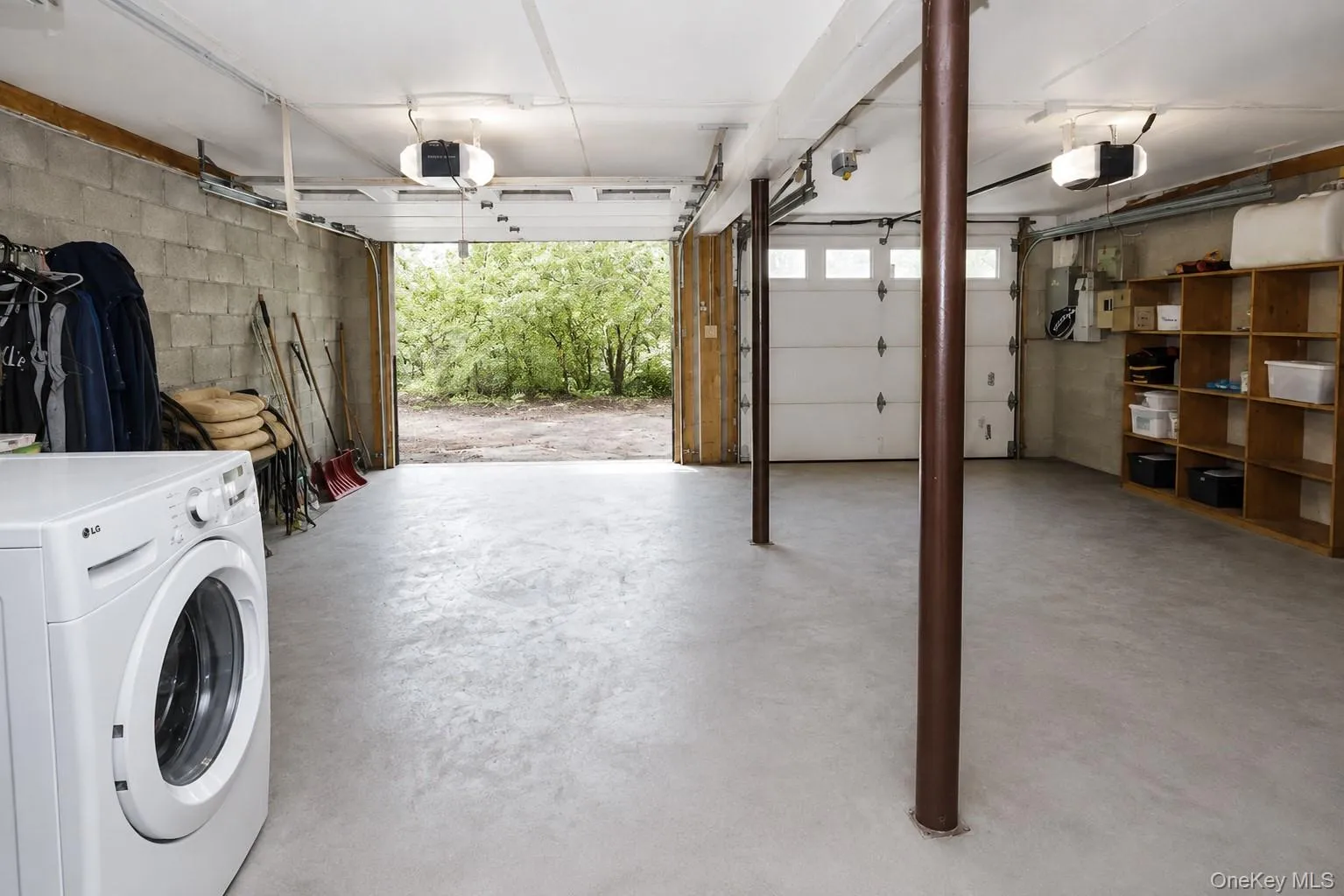 Spacious garage featuring a concrete floor, exposed block wall, and two overhead garage doors Spacious garage featuring a concrete floor, exposed block wall, and two overhead garage doors