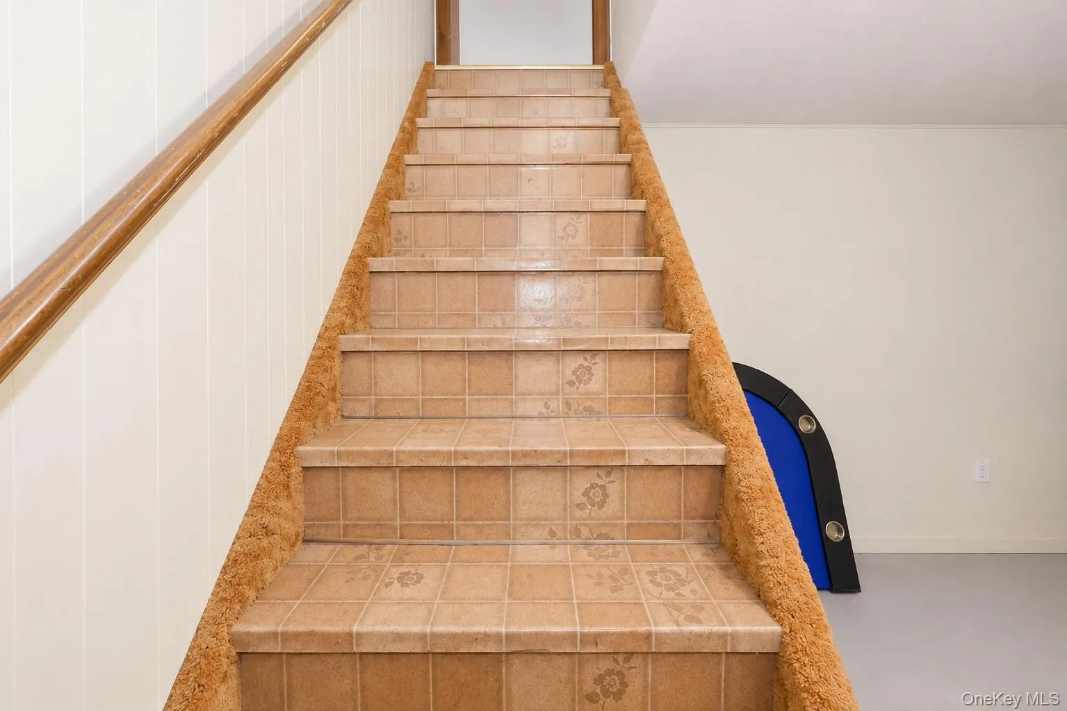 Staircase with patterned tile treads and risers, complemented by a wood handrail Staircase with patterned tile treads and risers, complemented by a wood handrail