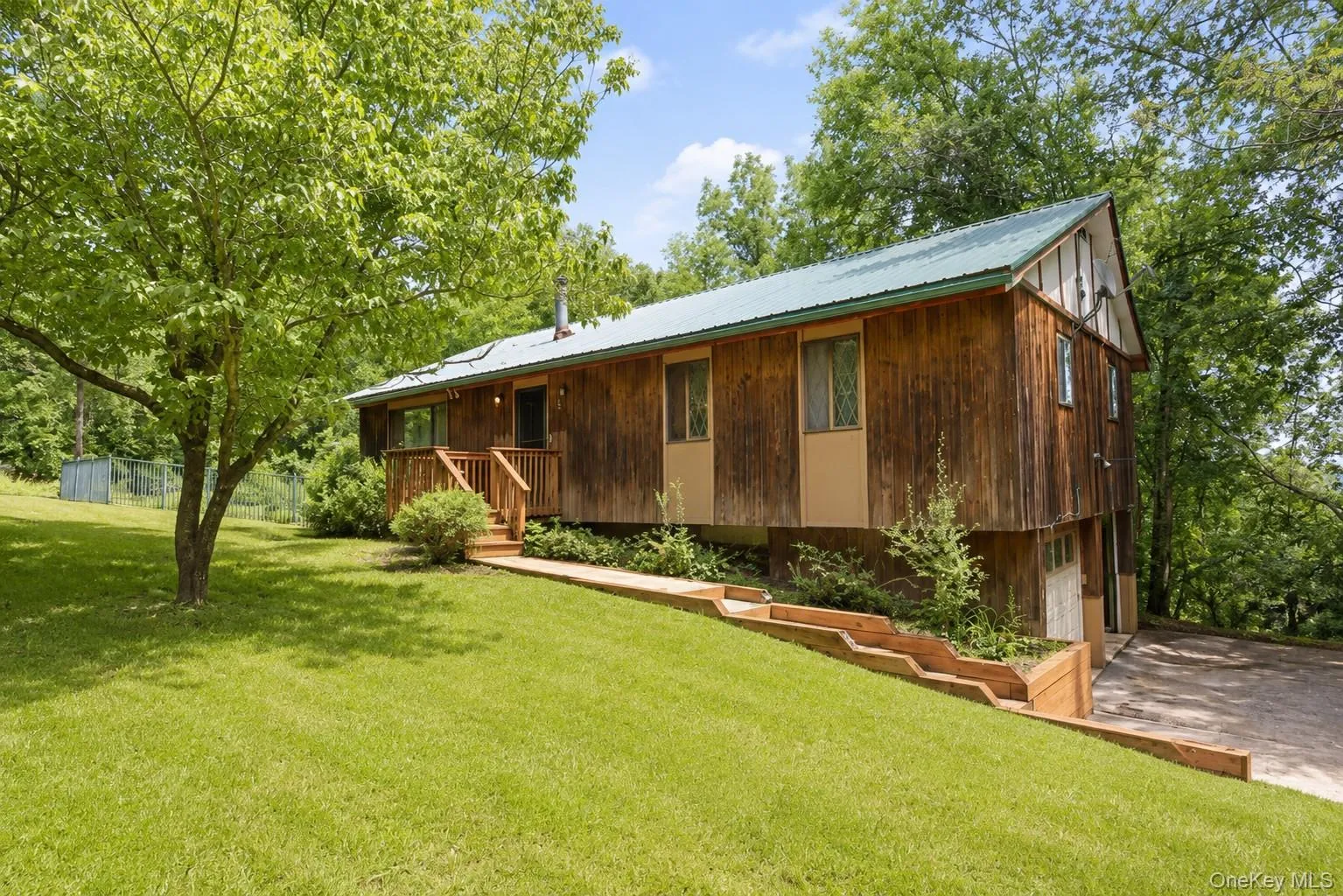 Wood-sided exterior featuring a green metal roof and a prominent front porch with wood railings Wood-sided exterior featuring a green metal roof and a prominent front porch with wood railings