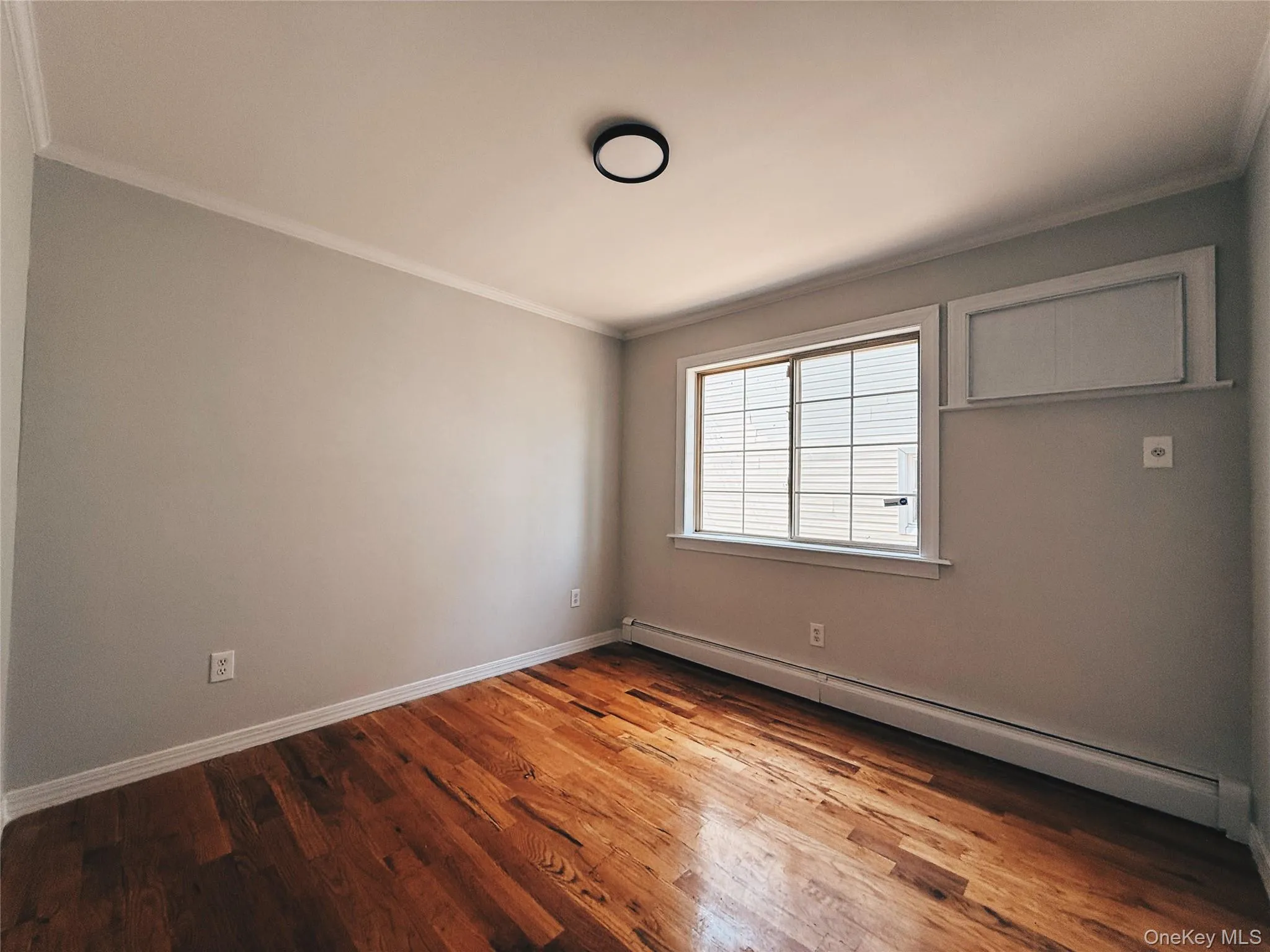 Hardwood flooring throughout featuring a window with horizontal blinds, baseboard heating, closet, and a flush-mount ceiling light fixture. Hardwood flooring throughout featuring a window with horizontal blinds, baseboard heating, closet, and a flush-mount ceiling light fixture.