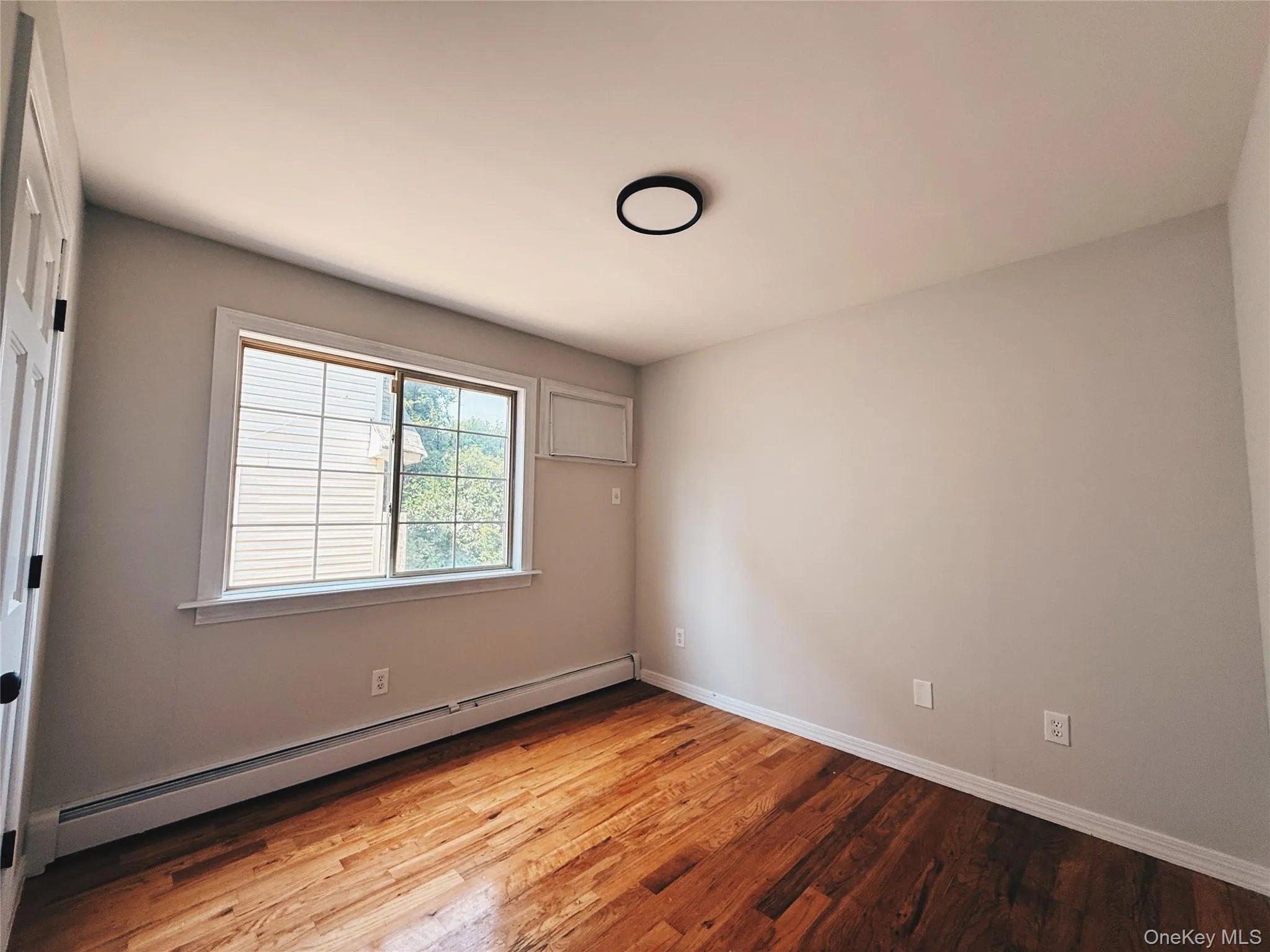 Hardwood flooring featuring warm tones, closet, a double-hung window, and a contemporary ceiling light fixture. Hardwood flooring featuring warm tones, closet, a double-hung window, and a contemporary ceiling light fixture.