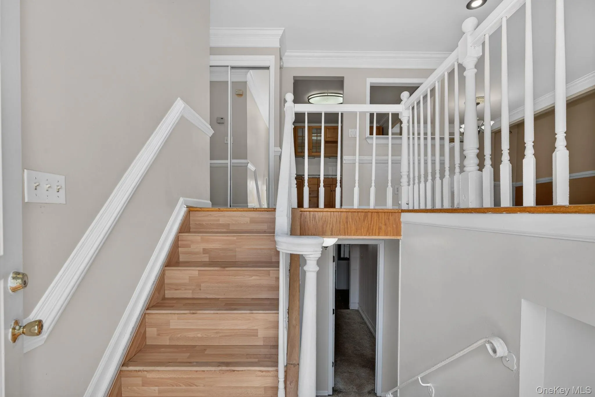 Split-level entry with wood-finish stairs, white baluster railing, and white crown molding Split-level entry with wood-finish stairs, white baluster railing, and white crown molding