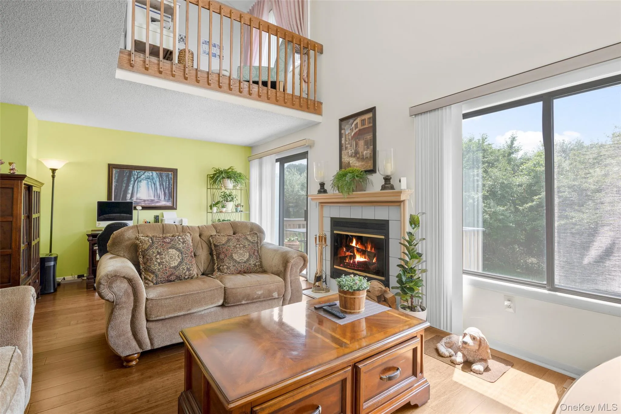 Photo shows Loft above plus lovely Treetop views through windows & door to Deck. Anchored by the cozy Fireplace, Living room extends to far wall with section under loft currently being used as an office space. Photo shows Loft above plus lovely Treetop views through windows & door to Deck. Anchored by the cozy Fireplace, Living room extends to far wall with section under loft currently being used as an office space.