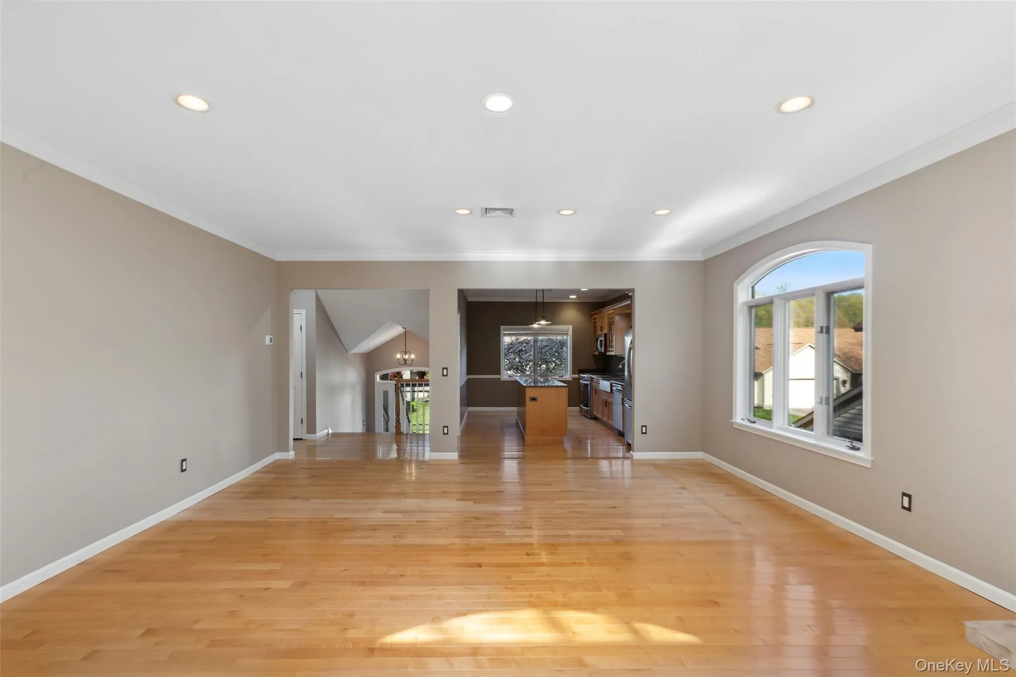 Unfurnished living room with recessed lighting, ornamental molding, and light wood-style floors Unfurnished living room with recessed lighting, ornamental molding, and light wood-style floors