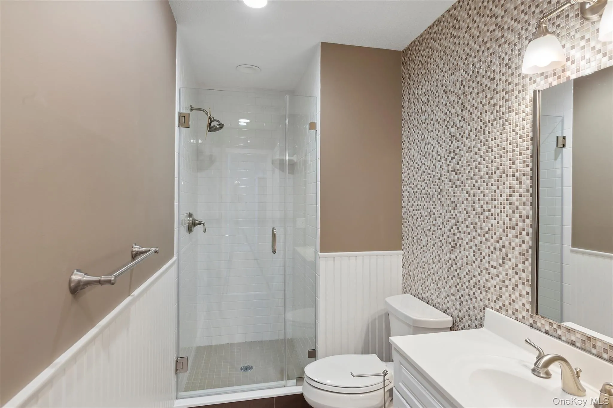 Full bath featuring wainscoting, toilet, a shower stall, and vanity Full bath featuring wainscoting, toilet, a shower stall, and vanity