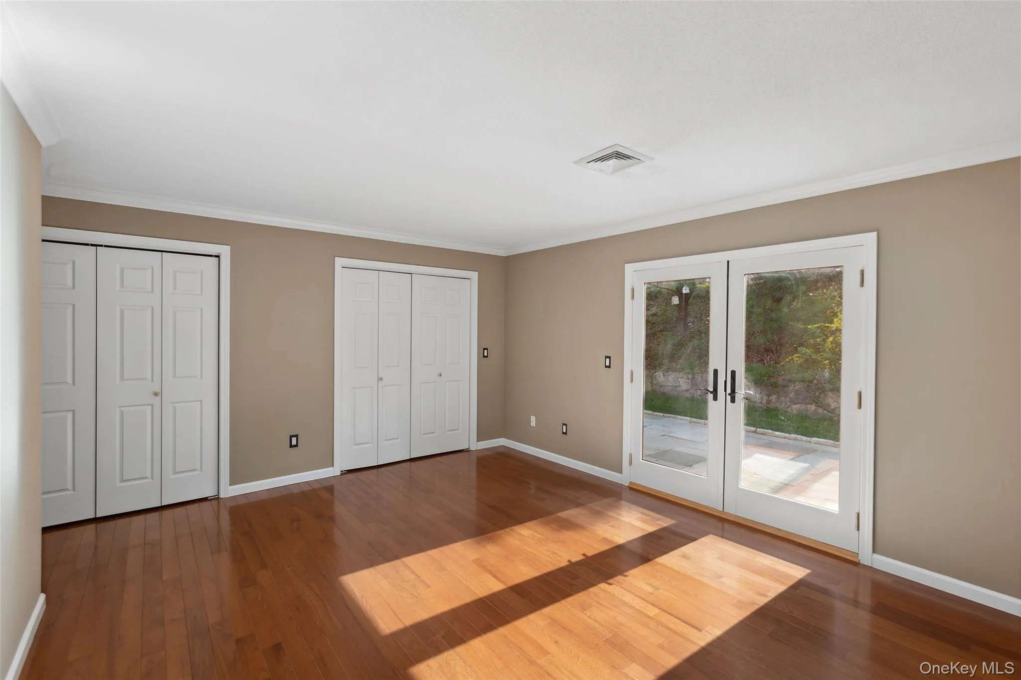 Unfurnished bedroom with french doors, wood finished floors, baseboards, multiple closets, and access to outside Unfurnished bedroom with french doors, wood finished floors, baseboards, multiple closets, and access to outside