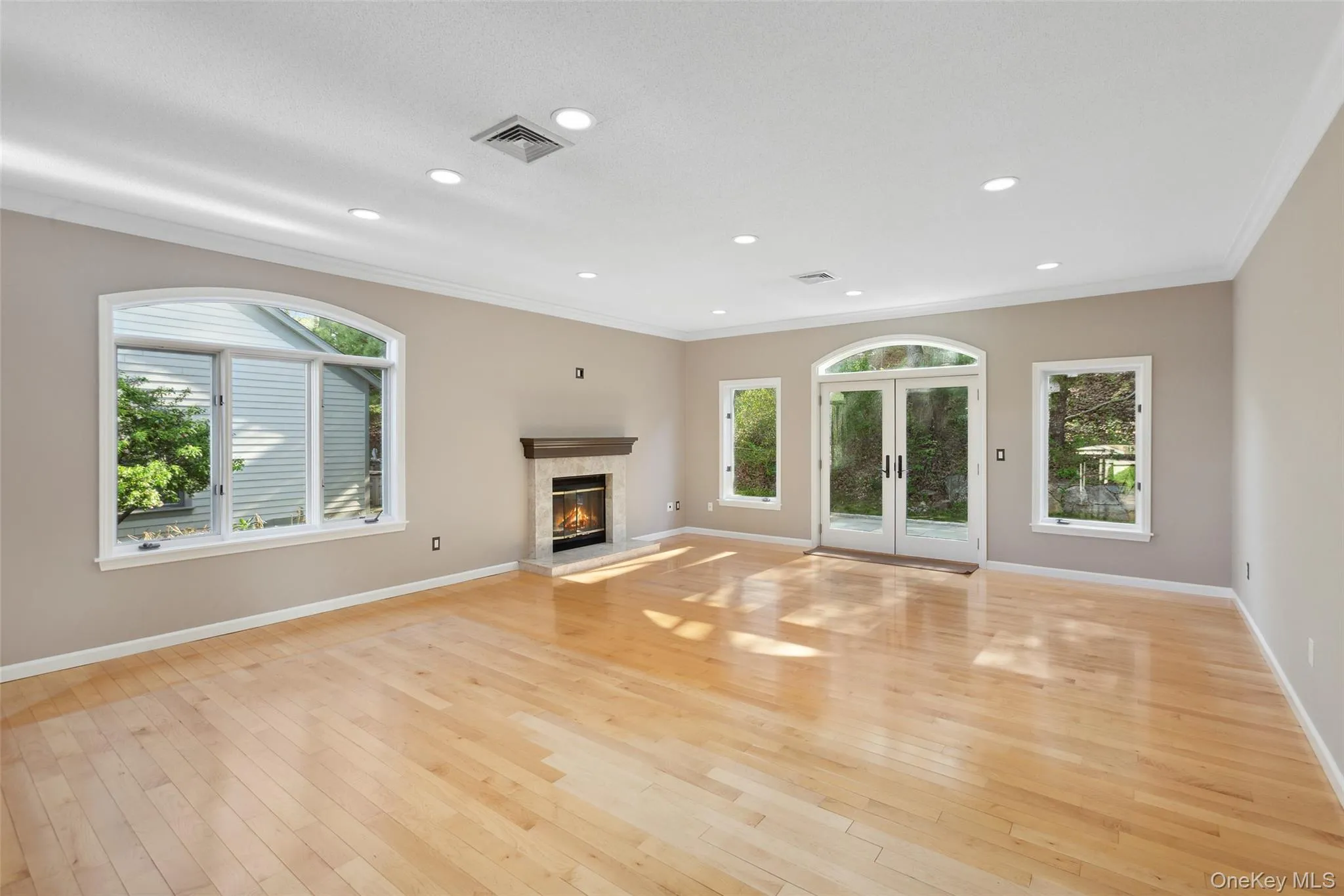 Unfurnished living room featuring french doors, ornamental molding, visible vents, and a high end fireplace Unfurnished living room featuring french doors, ornamental molding, visible vents, and a high end fireplace
