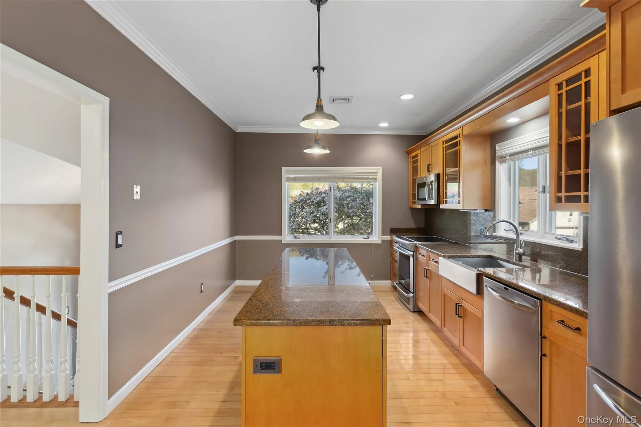 Kitchen featuring appliances with stainless steel finishes, a center island, a sink, dark stone counters, and light wood-style flooring Kitchen featuring appliances with stainless steel finishes, a center island, a sink, dark stone counters, and light wood-style flooring