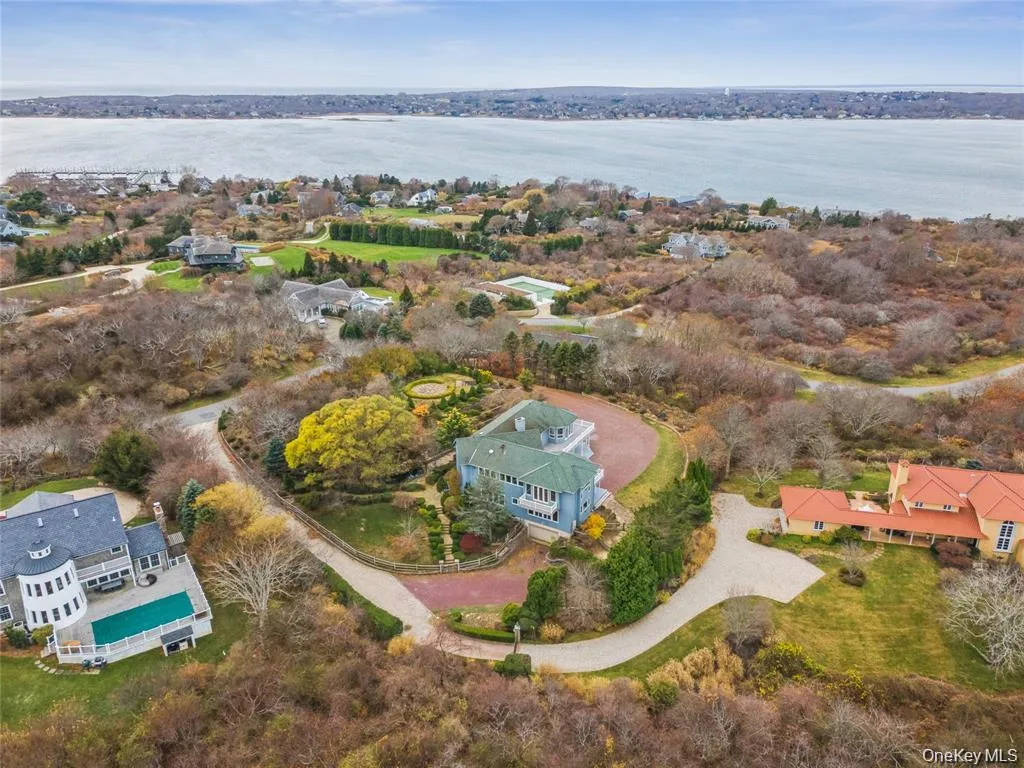 Expansive property featuring three distinct residences, a large body of water in the background, mature landscaping, and curved driveways Expansive property featuring three distinct residences, a large body of water in the background, mature landscaping, and curved driveways
