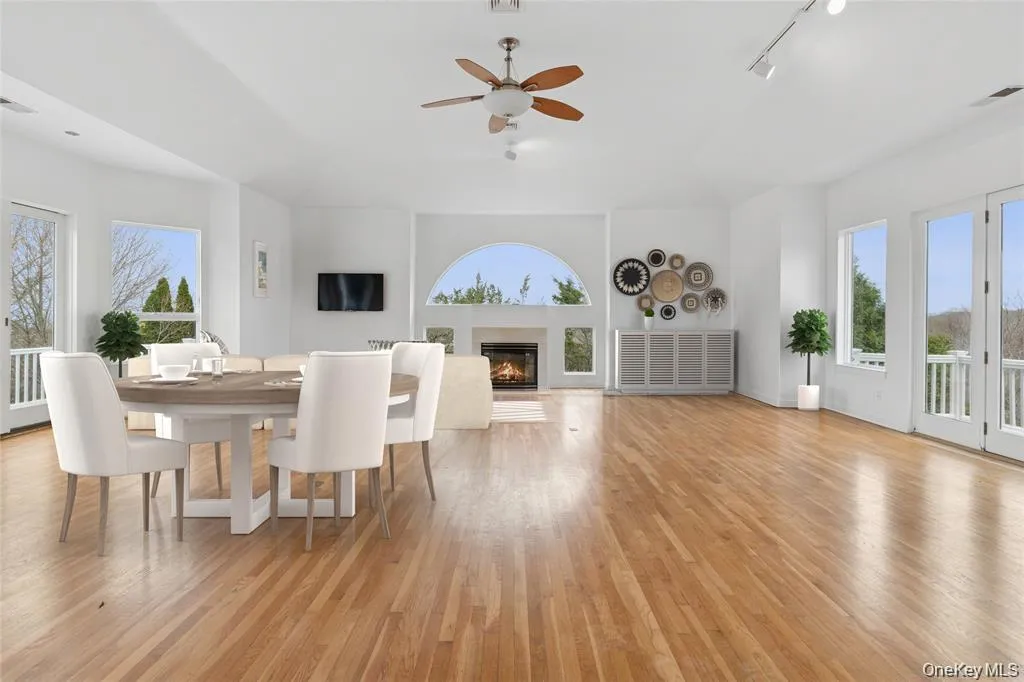 Spacious living area featuring wood-finish flooring, a ceiling fan, and recessed lighting Spacious living area featuring wood-finish flooring, a ceiling fan, and recessed lighting