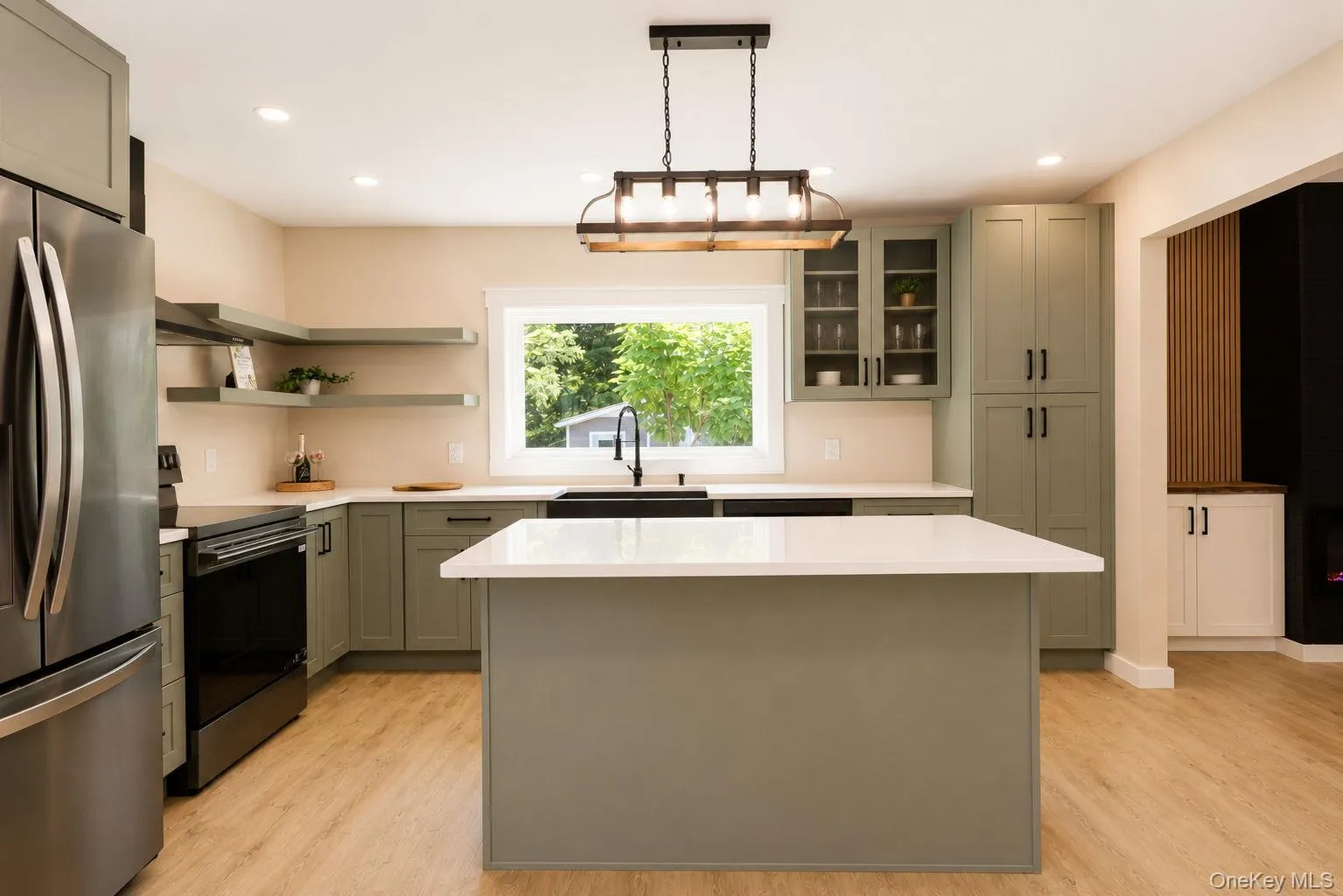 Contemporary kitchen featuring light green cabinetry, white countertops, and wood-finish flooring Contemporary kitchen featuring light green cabinetry, white countertops, and wood-finish flooring