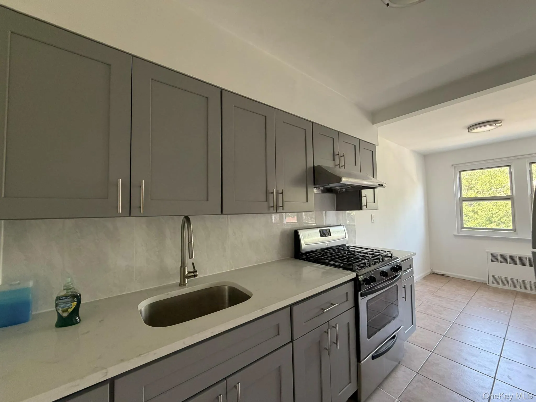 Kitchen featuring gray shaker-style cabinetry, a stainless steel gas range, and a coordinating range hood Kitchen featuring gray shaker-style cabinetry, a stainless steel gas range, and a coordinating range hood