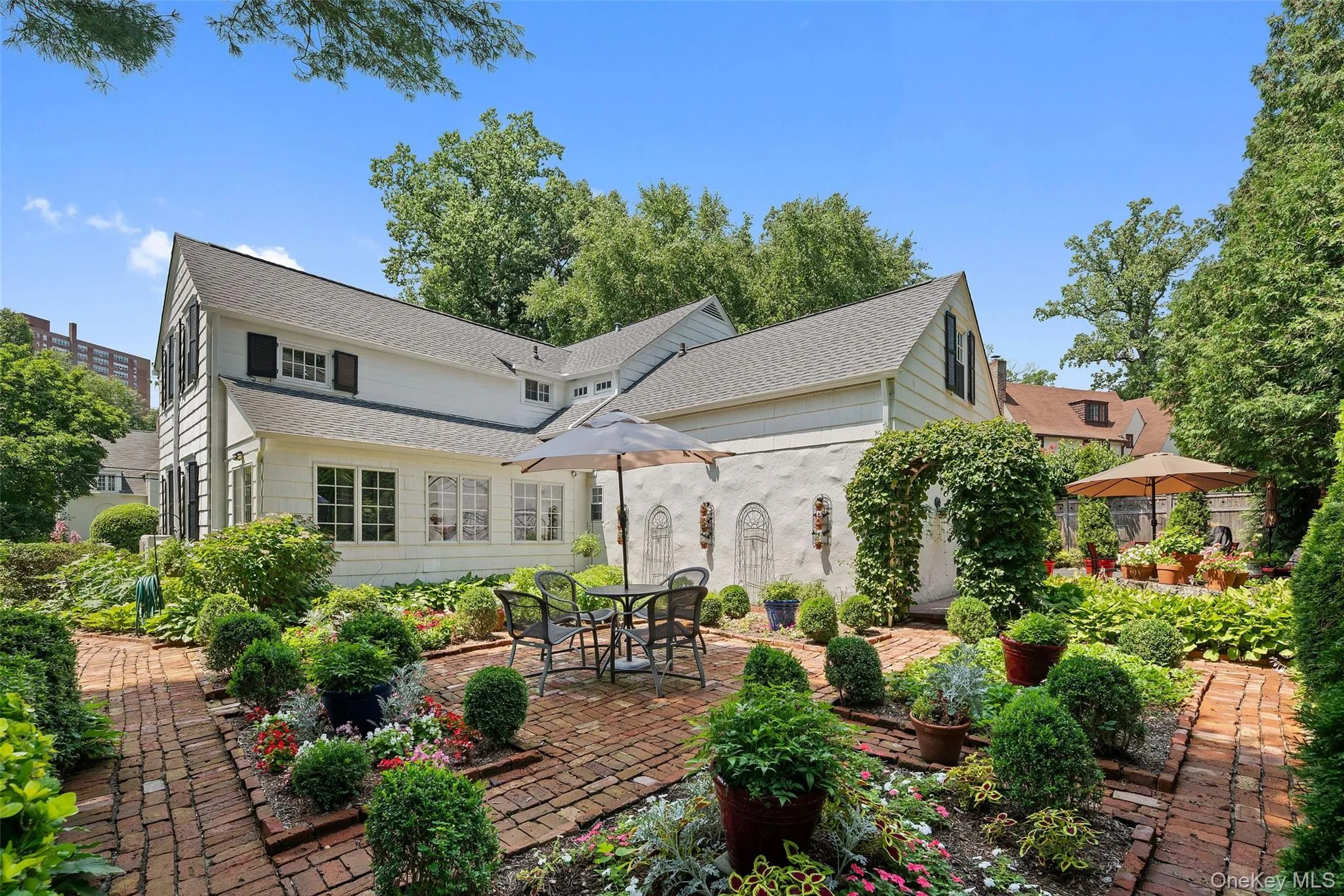 View of the rear of the home featuring the gardens and brick patios. View of the rear of the home featuring the gardens and brick patios.