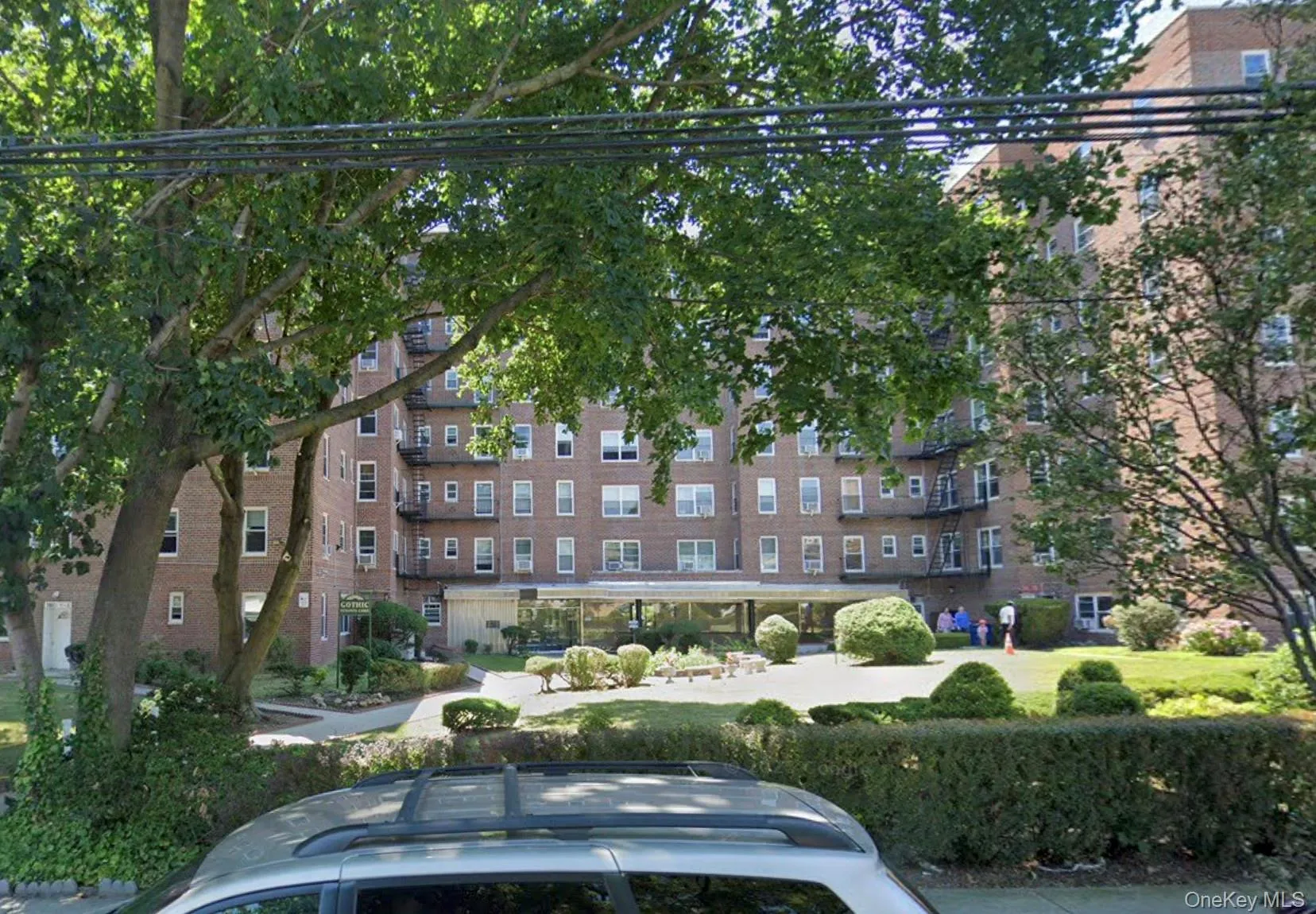 Brick multi-story building featuring multiple balconies, fire escapes, and a covered entry Brick multi-story building featuring multiple balconies, fire escapes, and a covered entry