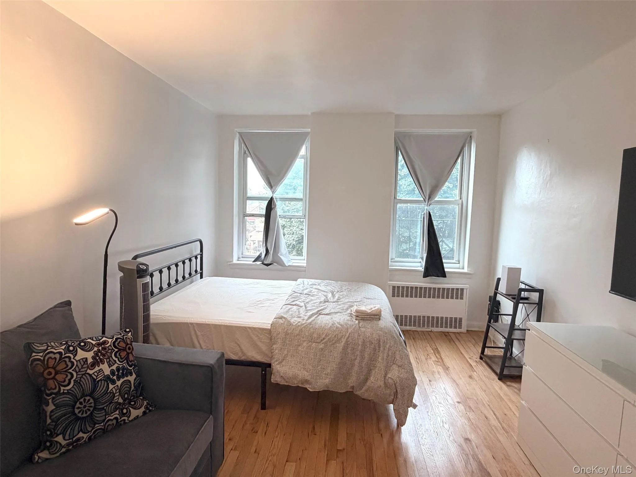 Bright room with two windows, wood-finish flooring, and white walls Bright room with two windows, wood-finish flooring, and white walls