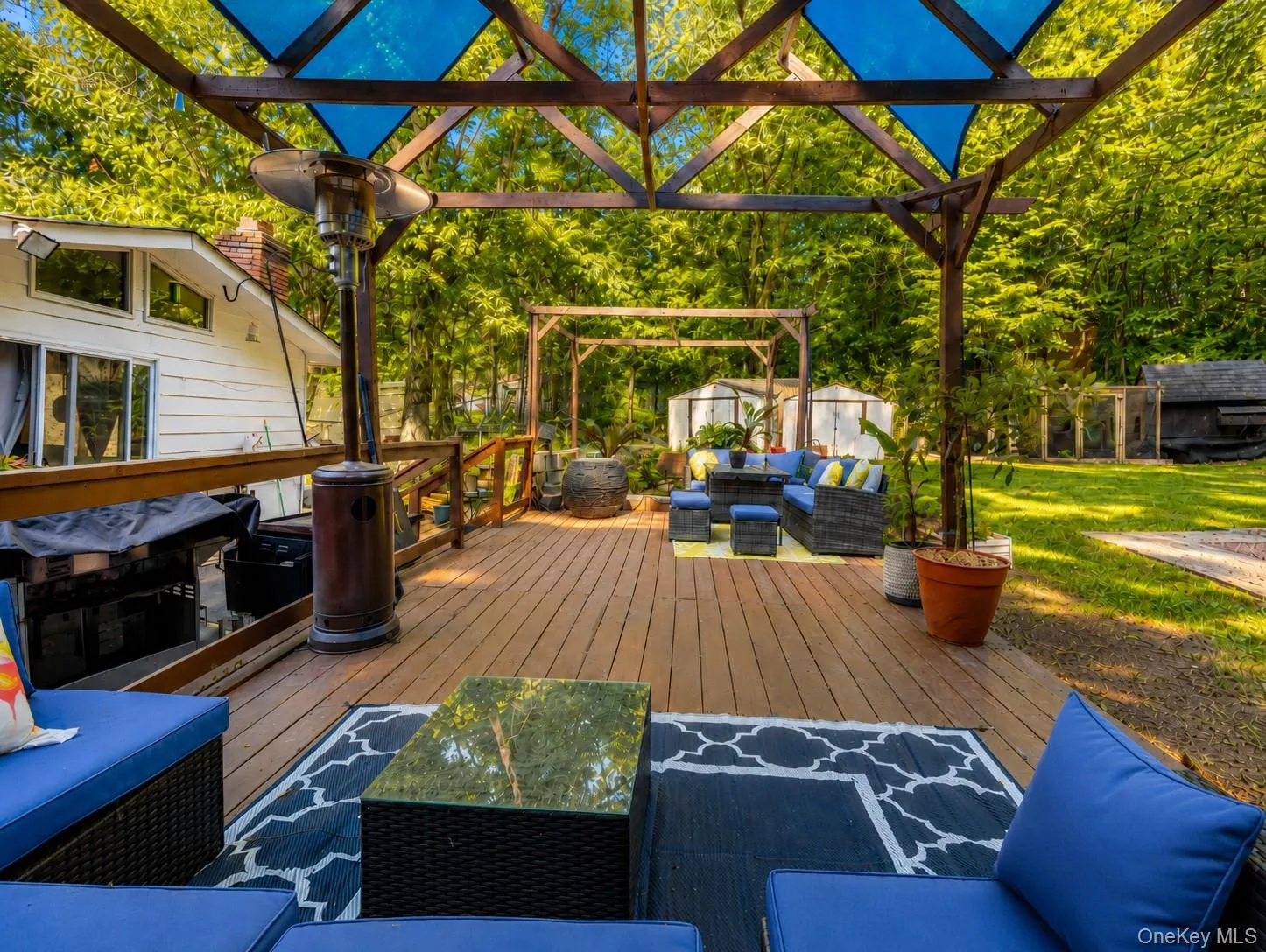 Expansive deck featuring wood-finish flooring and a sturdy pergola structure with cross-bracing, providing ample shaded outdoor entertaining space Expansive deck featuring wood-finish flooring and a sturdy pergola structure with cross-bracing, providing ample shaded outdoor entertaining space