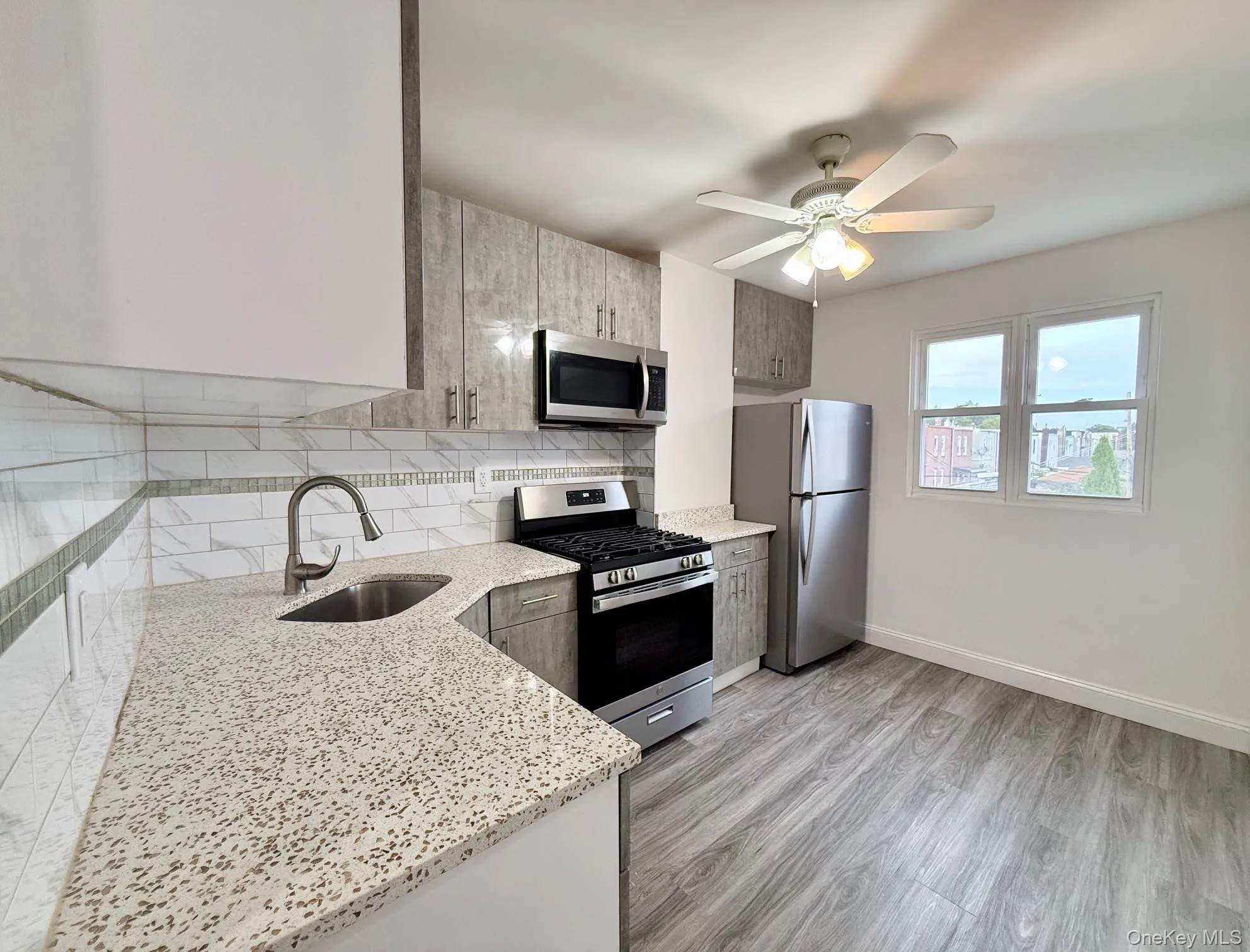 Kitchen featuring light wood-finish cabinetry, stainless steel appliances, speckled countertops, and a white subway tile backsplash Kitchen featuring light wood-finish cabinetry, stainless steel appliances, speckled countertops, and a white subway tile backsplash