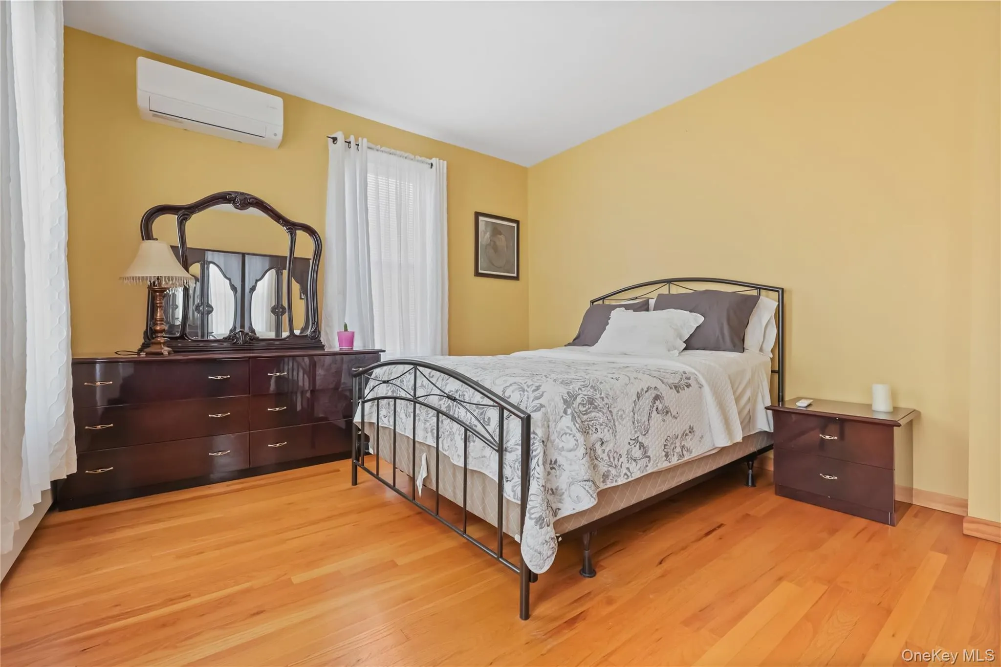 Bedroom with light wood-style flooring and a wall mounted AC Bedroom with light wood-style flooring and a wall mounted AC
