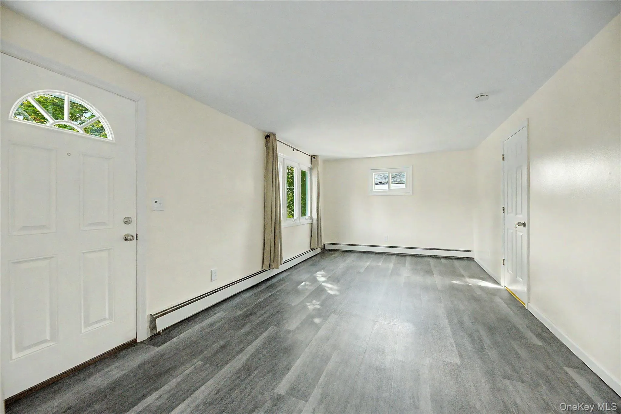 Wood-finish flooring, white paneled entry door with an arched window, multiple windows, and a white interior door Wood-finish flooring, white paneled entry door with an arched window, multiple windows, and a white interior door