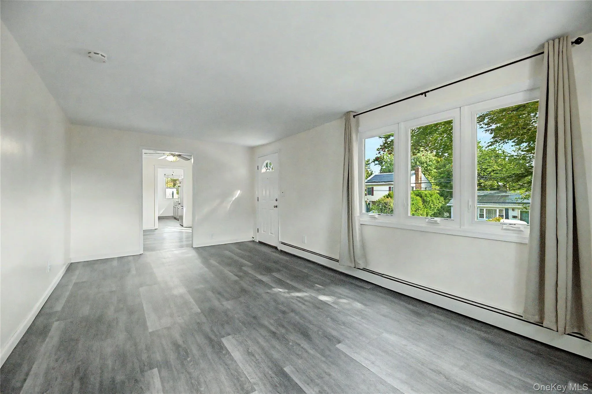 Wood-finish flooring, white paneled entry door with an arched window, multiple windows, and a white interior door Wood-finish flooring, white paneled entry door with an arched window, multiple windows, and a white interior door