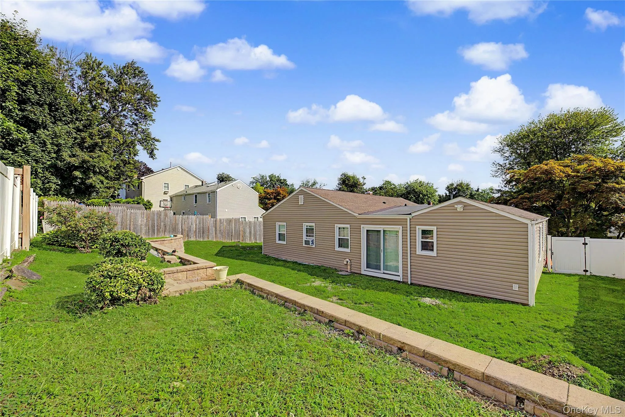 Expansive backyard with a terraced retaining wall, privacy fencing, and mature trees Expansive backyard with a terraced retaining wall, privacy fencing, and mature trees
