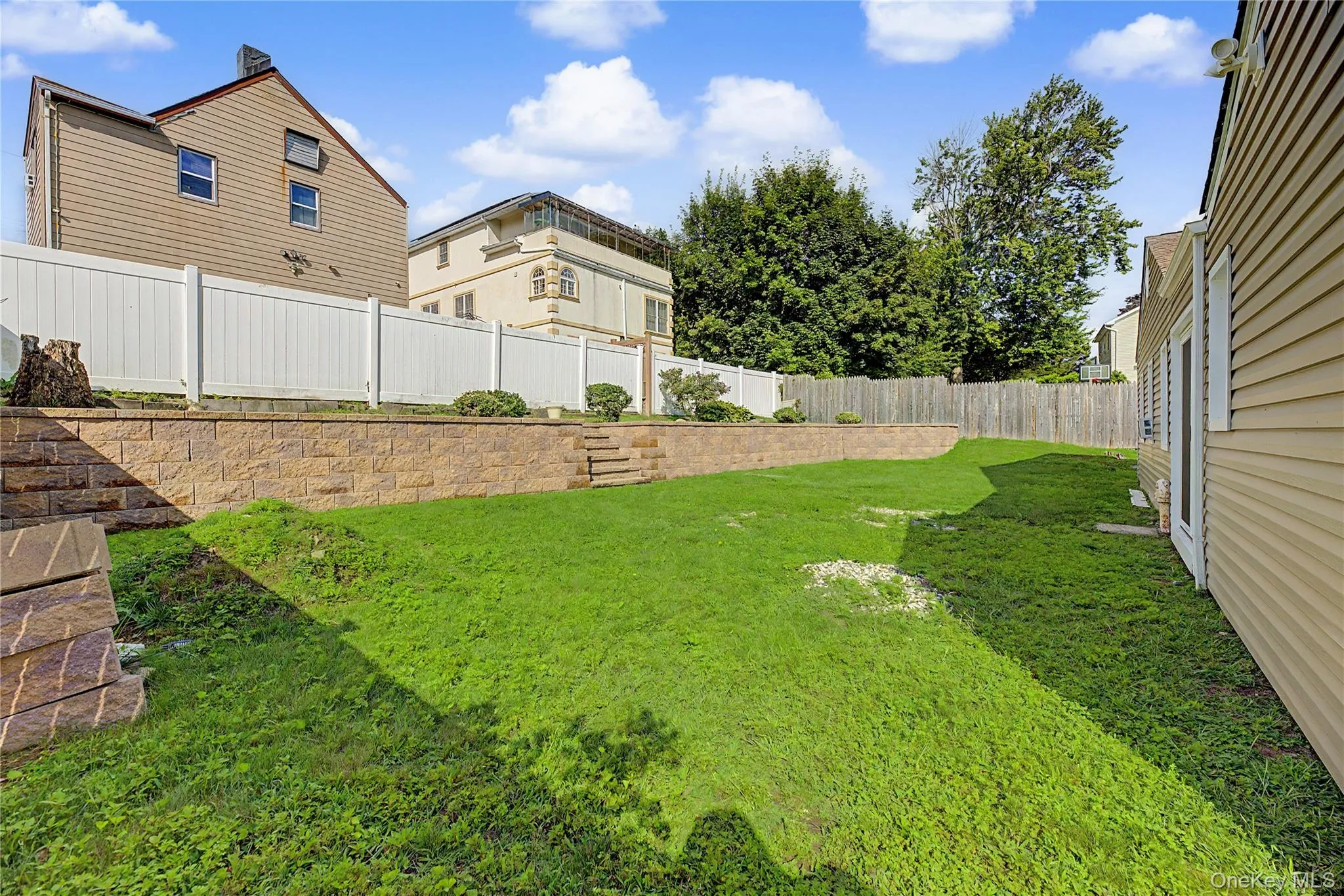 Expansive backyard with a terraced retaining wall, privacy fencing, and mature trees Expansive backyard with a terraced retaining wall, privacy fencing, and mature trees