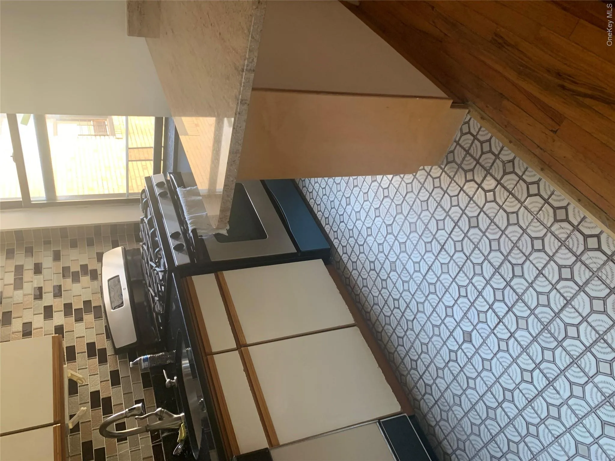 Kitchen featuring a stainless steel range, dark countertops, two-tone cabinetry, and a light-toned backsplash with varied tiling Kitchen featuring a stainless steel range, dark countertops, two-tone cabinetry, and a light-toned backsplash with varied tiling