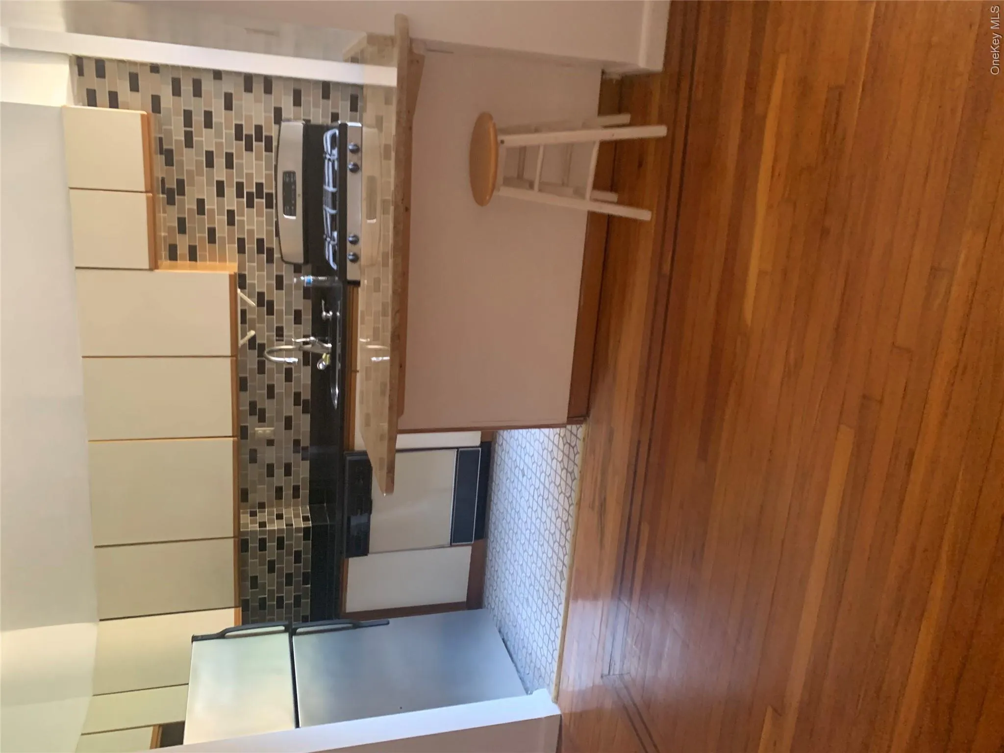 Kitchen featuring white upper cabinetry, black countertops, a mosaic tile backsplash, stainless steel refrigerator, and gas range Kitchen featuring white upper cabinetry, black countertops, a mosaic tile backsplash, stainless steel refrigerator, and gas range