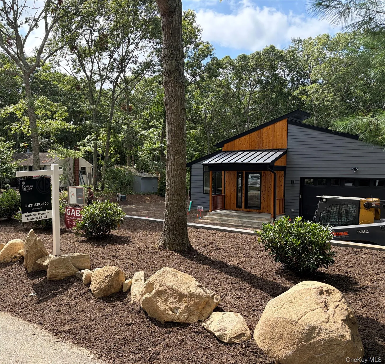 Modern exterior with wood siding accents, dark gray siding, a black metal roof, and an attached garage Modern exterior with wood siding accents, dark gray siding, a black metal roof, and an attached garage