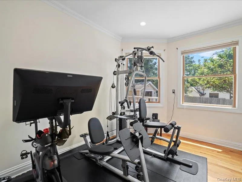 Exercise room with crown molding, baseboards, and wood finished floors Exercise room with crown molding, baseboards, and wood finished floors