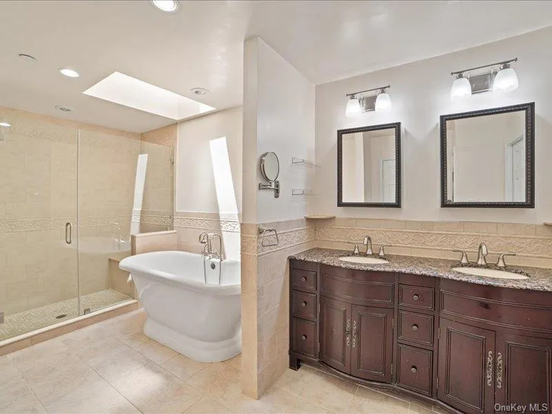 Full bath featuring a skylight, a shower stall, a freestanding tub, & double vanity, Full bath featuring a skylight, a shower stall, a freestanding tub, & double vanity,