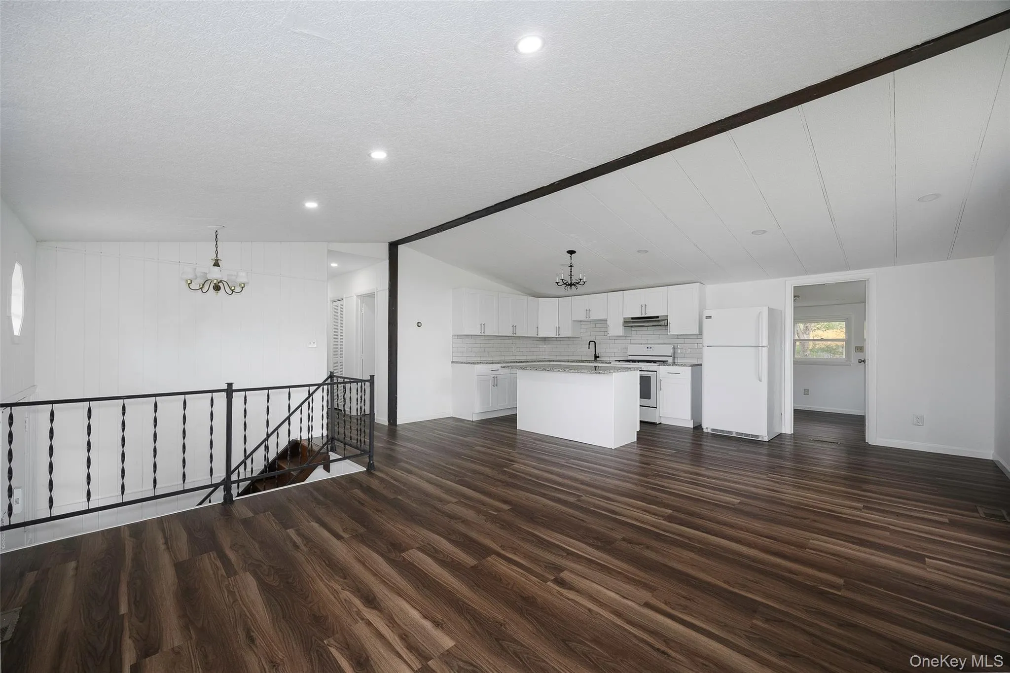Unfurnished living room featuring a chandelier, dark wood finished floors, lofted ceiling, and a textured ceiling Unfurnished living room featuring a chandelier, dark wood finished floors, lofted ceiling, and a textured ceiling