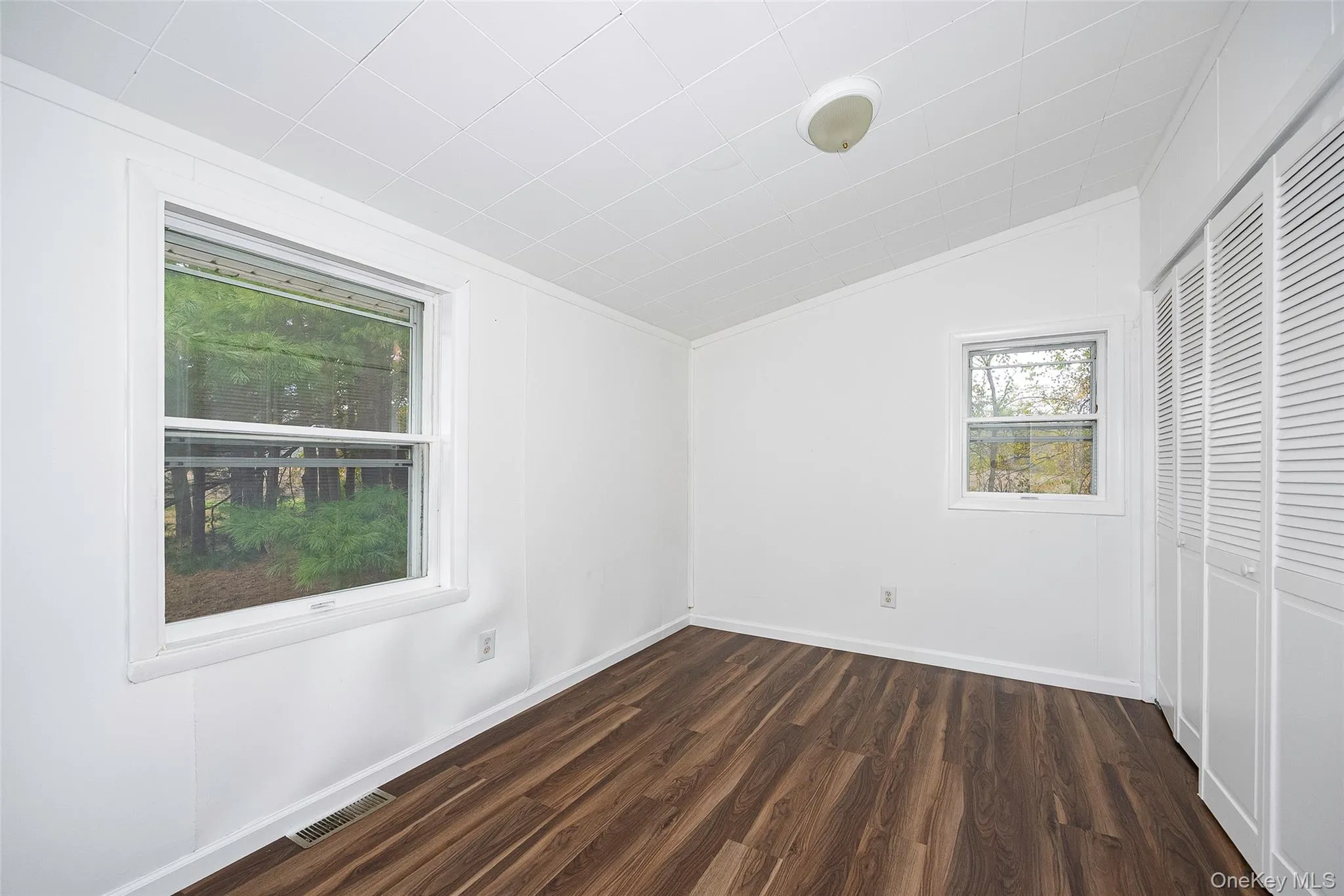Unfurnished bedroom with lofted ceiling, a closet, and dark wood finished floors Unfurnished bedroom with lofted ceiling, a closet, and dark wood finished floors