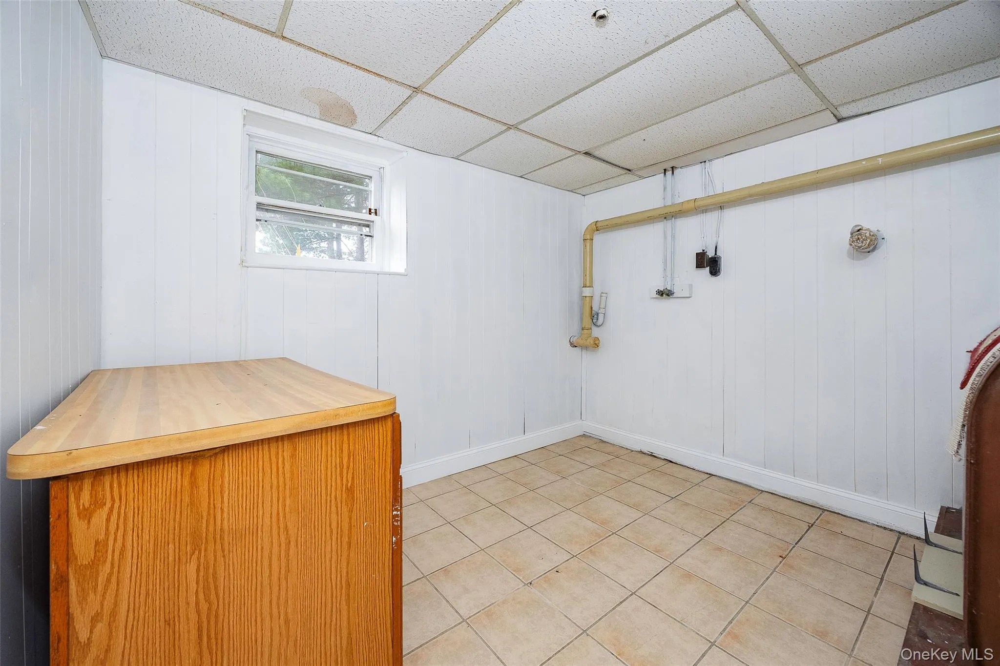 Washroom with tile patterned flooring, wooden walls, and a drop ceiling Washroom with tile patterned flooring, wooden walls, and a drop ceiling