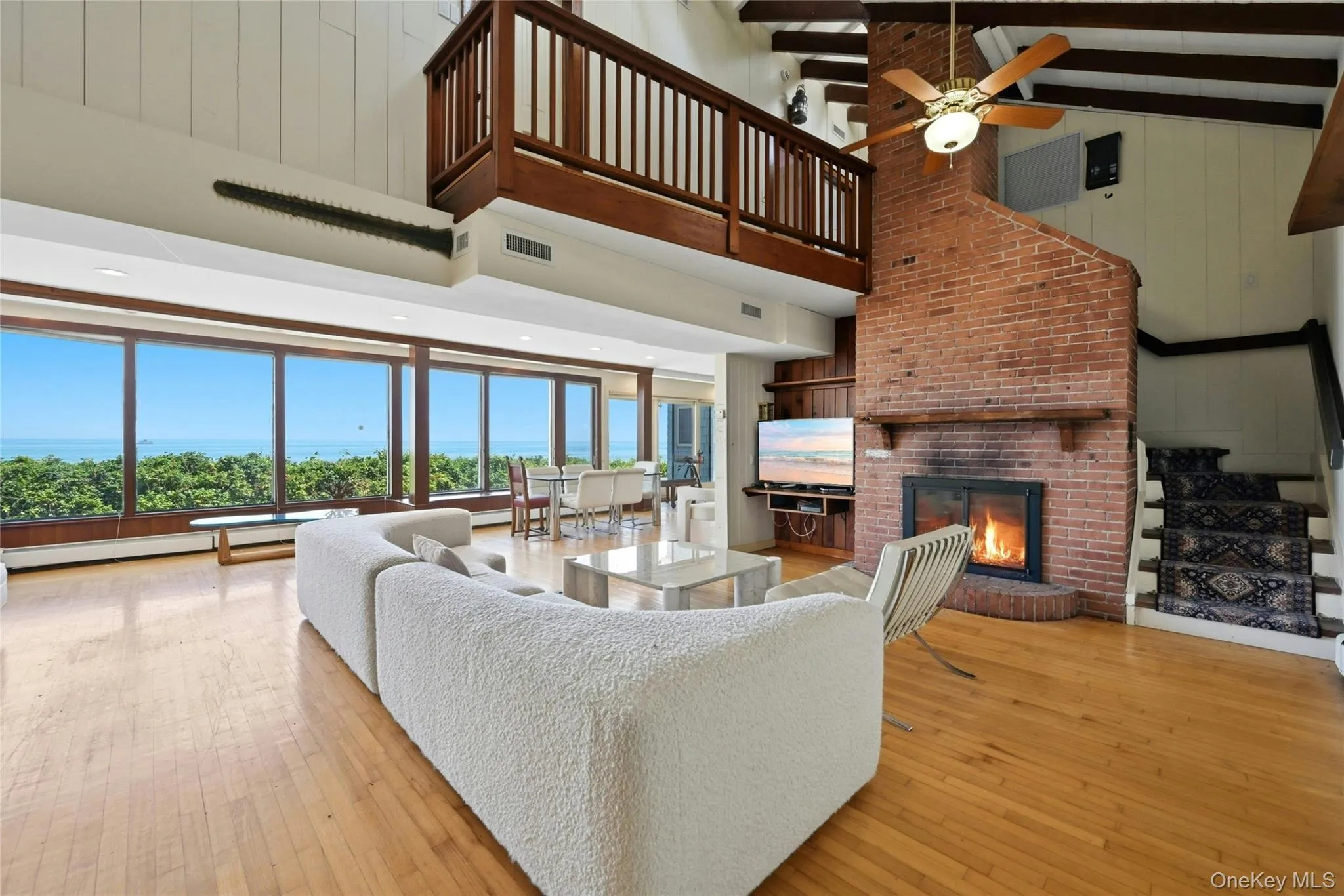 Great room with walls of glass, soaring beamed ceilings and fireplace Great room with walls of glass, soaring beamed ceilings and fireplace