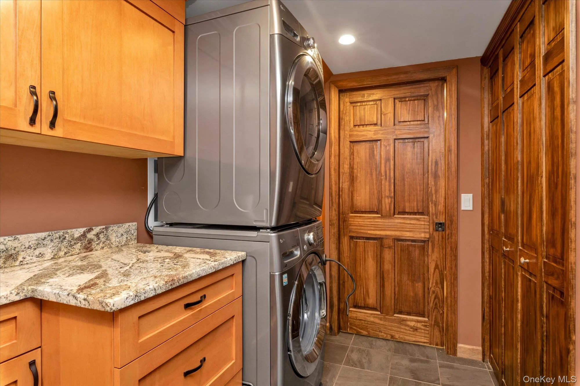 Massive laundry room with granite countertops, closet, storage and tile flooring. Massive laundry room with granite countertops, closet, storage and tile flooring.