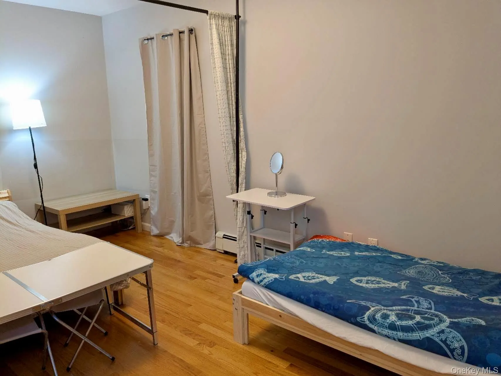 Room with wood-finish flooring, light gray walls, and baseboard heating Room with wood-finish flooring, light gray walls, and baseboard heating