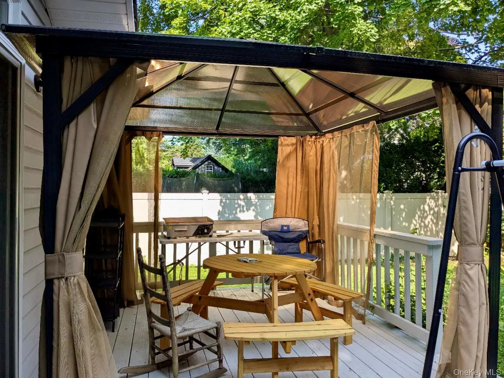 Deck space featuring a covered pergola with retractable privacy screens, white railing, and exterior wall siding Deck space featuring a covered pergola with retractable privacy screens, white railing, and exterior wall siding