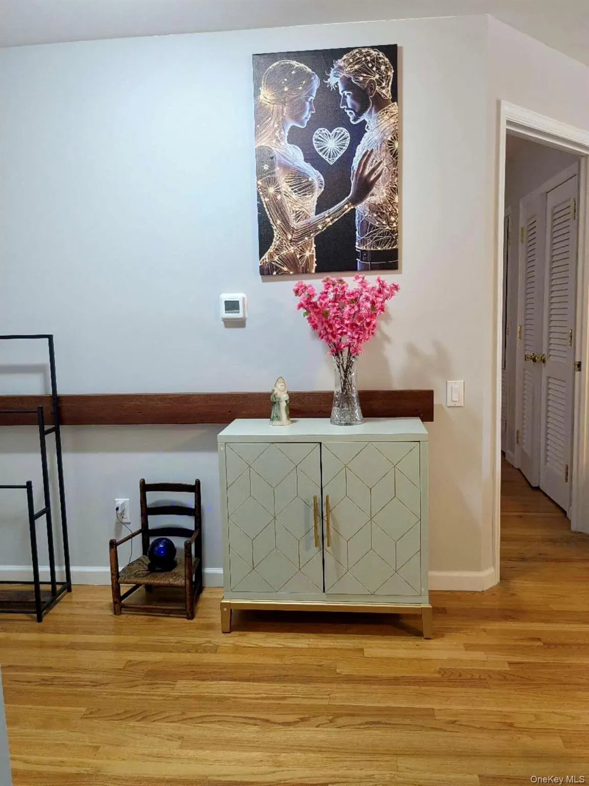 Hardwood flooring throughout featuring a light grey cabinet with geometric detailing and gold-tone hardware Hardwood flooring throughout featuring a light grey cabinet with geometric detailing and gold-tone hardware