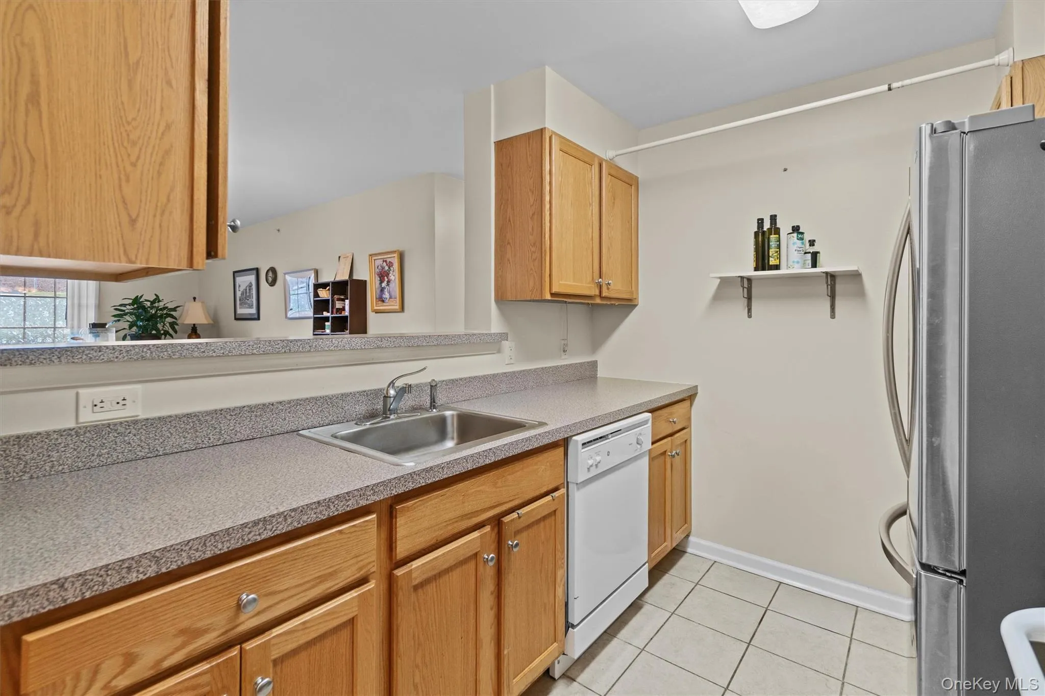Kitchen with white dishwasher, a sink, freestanding refrigerator, and light tile patterned flooring Kitchen with white dishwasher, a sink, freestanding refrigerator, and light tile patterned flooring