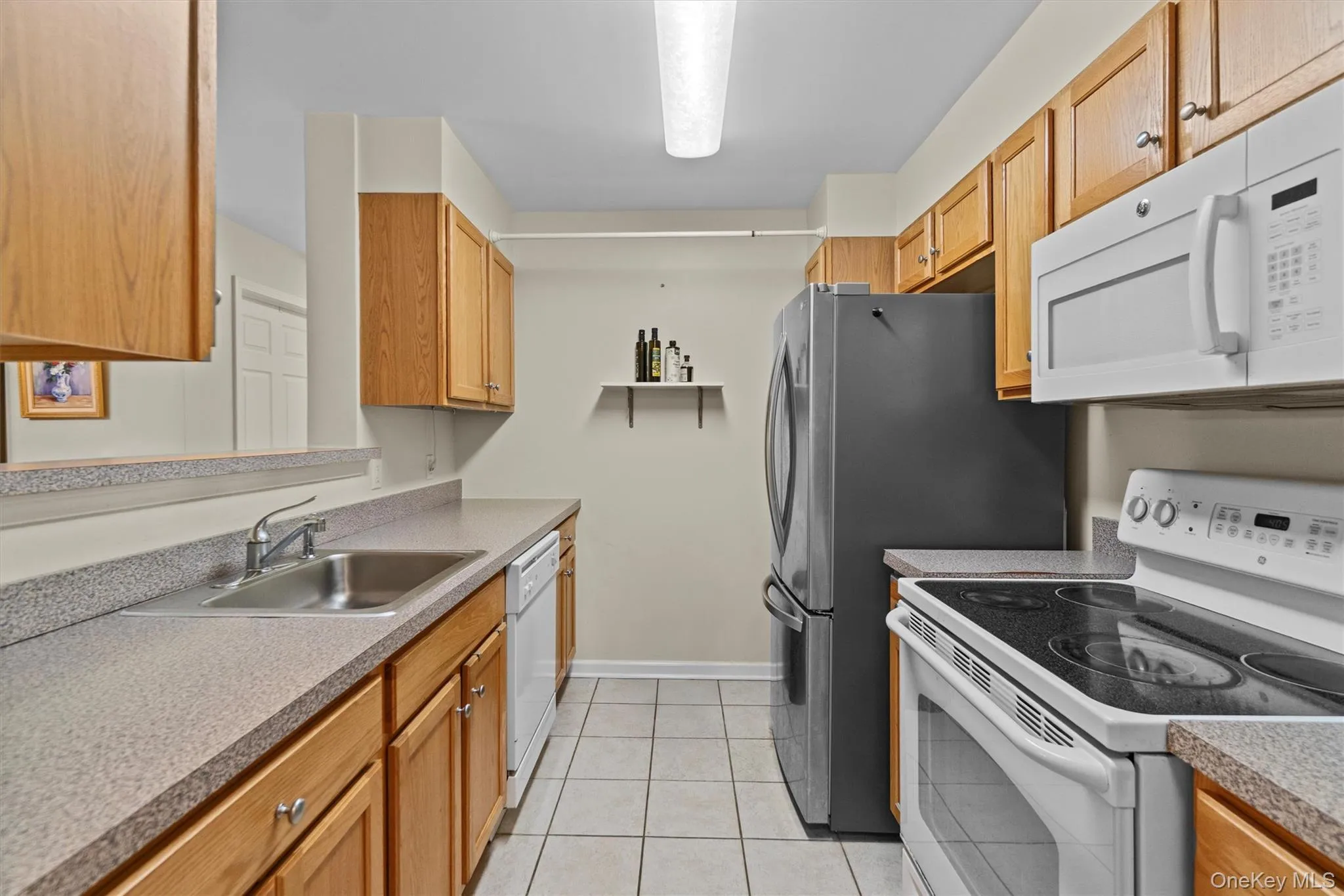 Kitchen featuring white appliances, a sink, and light tile patterned floors Kitchen featuring white appliances, a sink, and light tile patterned floors