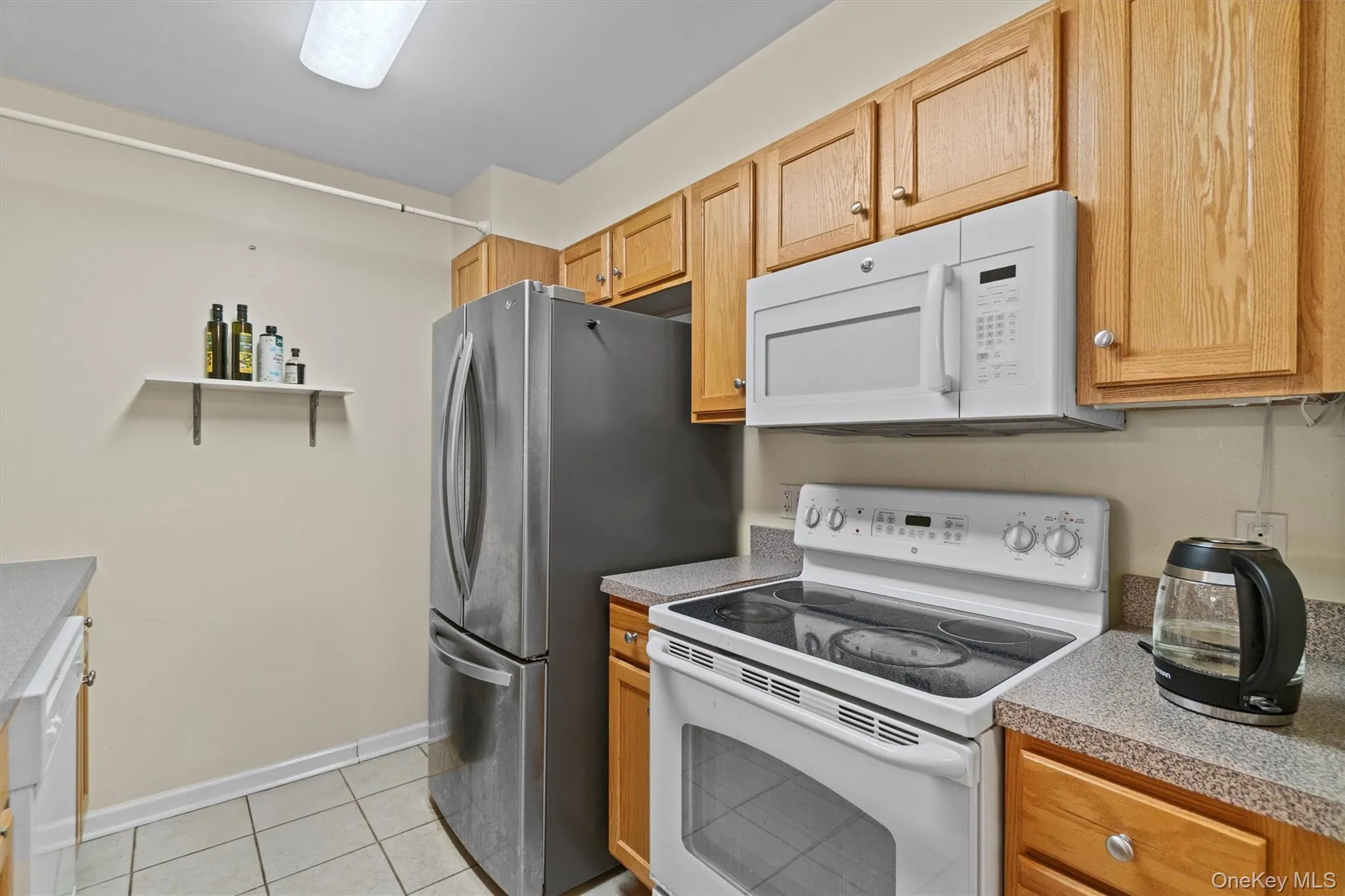 Kitchen with light countertops, light tile patterned flooring, and white appliances Kitchen with light countertops, light tile patterned flooring, and white appliances