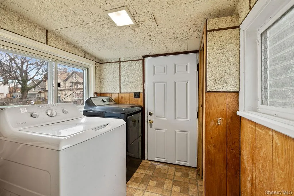 Laundry room featuring independent washer and dryer and wood walls Laundry room featuring independent washer and dryer and wood walls