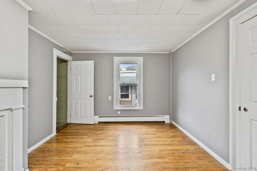 Unfurnished bedroom with light hardwood / wood-style floors, baseboard heating, and ornamental molding Unfurnished bedroom with light hardwood / wood-style floors, baseboard heating, and ornamental molding