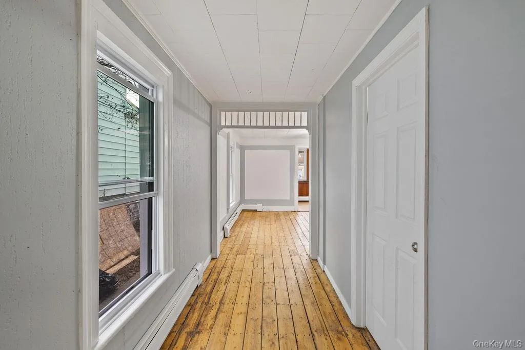 Hall with a healthy amount of sunlight, crown molding, and wood-type flooring Hall with a healthy amount of sunlight, crown molding, and wood-type flooring